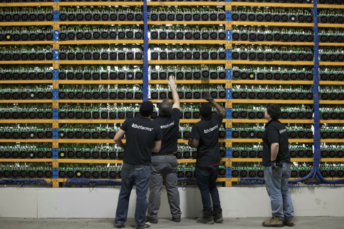 Employees check fans on mining machines at the Bitfarms cryptocurrency farming facility in Farnham, Quebec, Canada