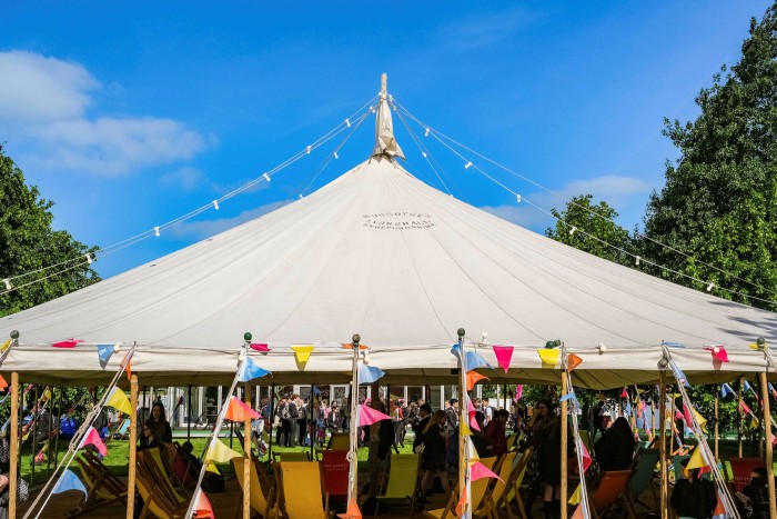 A big white tent adorned with bunting under a sunny sky