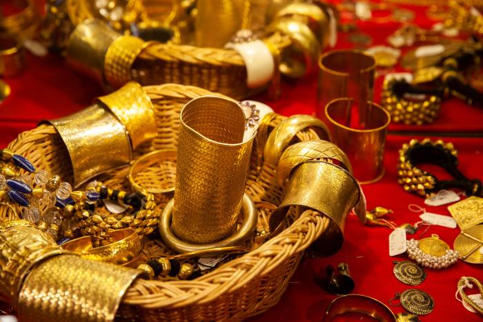 Gold jewellery in a basket on a red table