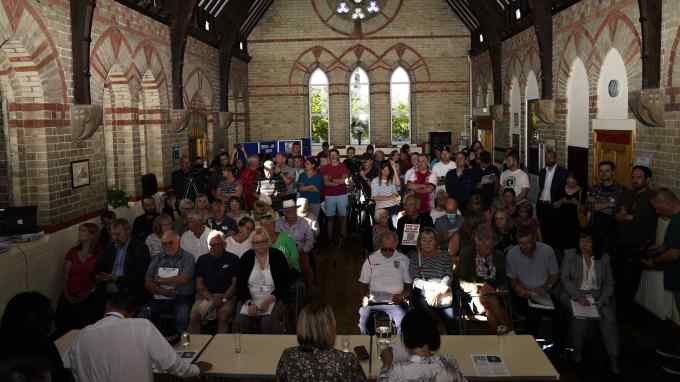 People attend the parish council meeting  at a town hall