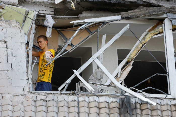 A resident inspects bomb damage to an apartment block in