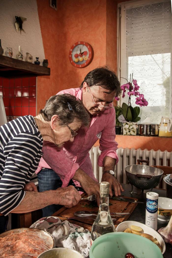 The chef Raymond Blanc cooking with his elderly mother in the kitchen of the family home in France in 2013. They are leaning over a table on which there are various ingredients and bowls 