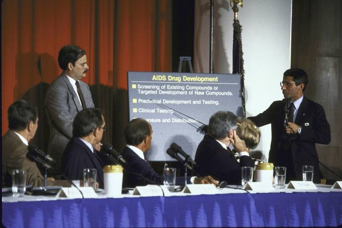 Fauci (right) lectures to the President’s Commission on Aids in 1987, with Ronald Reagan on the far left