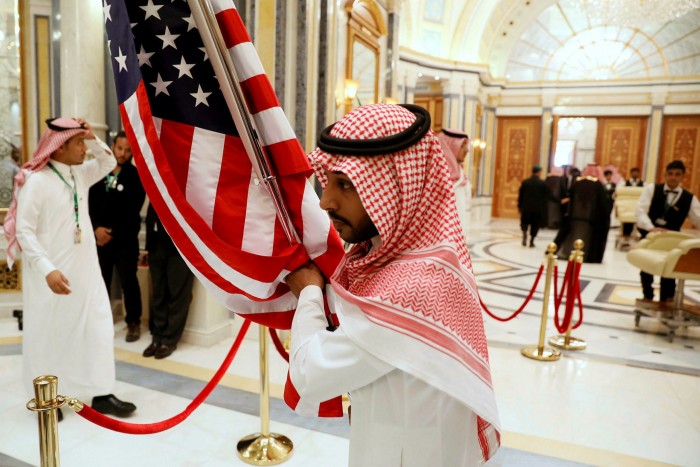A worker carries a US flag into a meeting room in Riyadh, Saudi Arabia