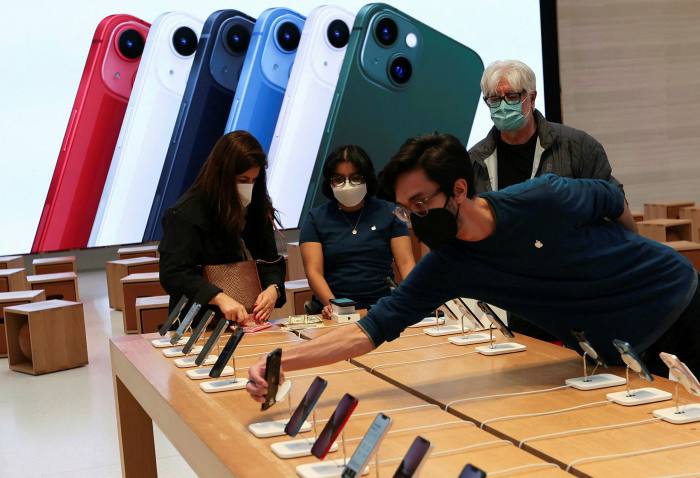 An employee arranges Apple iPhones as customer shop at the Apple Store