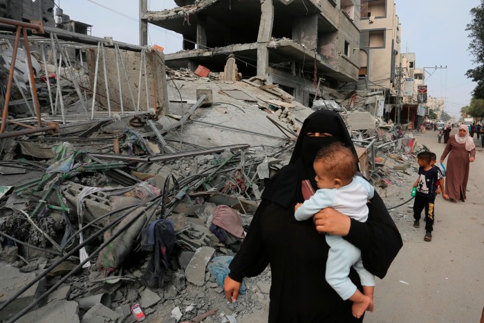 Palestijnen passeren zaterdag verwoeste gebouwen na Israëlische luchtaanvallen