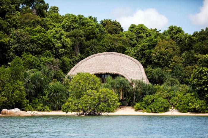 Surrounded by trees, a bamboo villa sits by the ocean in Cempedak