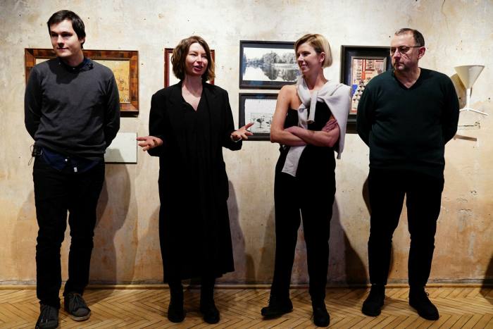 Cuatro figuras del mundo del arte, dos hombres y dos mujeres, en una presentación en una galería de arte