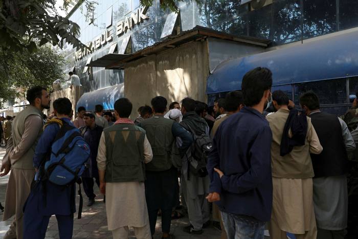 Los afganos esperan durante horas en largas filas para retirar dinero frente a una sucursal bancaria en Kabul en las horas previas a la llegada de los talibanes a la capital. 