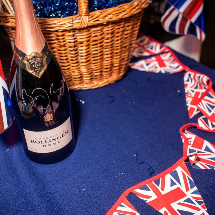 A string of union flags on a table where there is a basket and a bottle of champagne