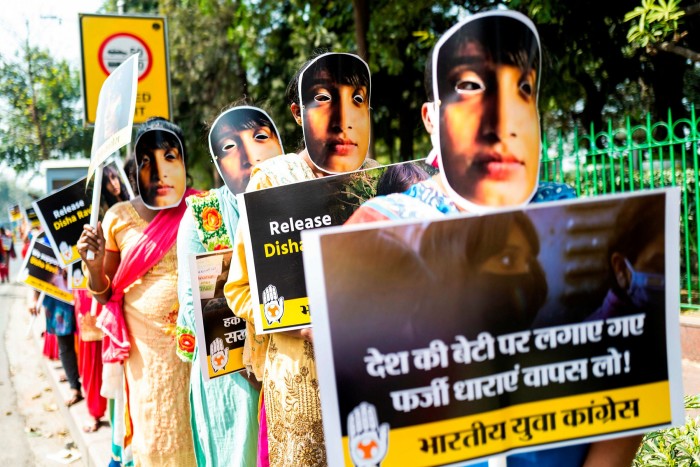 Indian Youth Congress activists and supporters wear masks of environmental activist Disha Ravi in New Delhi last month to protest against Ravi’s arrest  and the recent fuel price rise