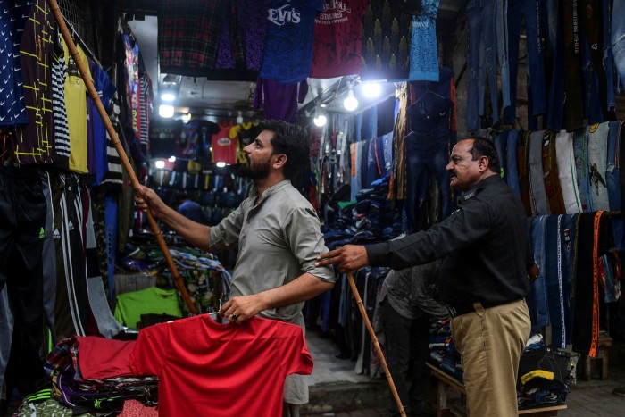 A policeman orders a Karachi shopkeeper to close down