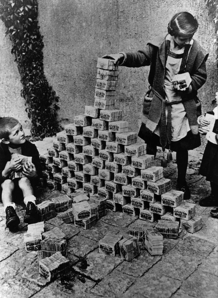 Dua kanak-kanak bermain menggunakan gumpalan wang tunai untuk blok bangunan