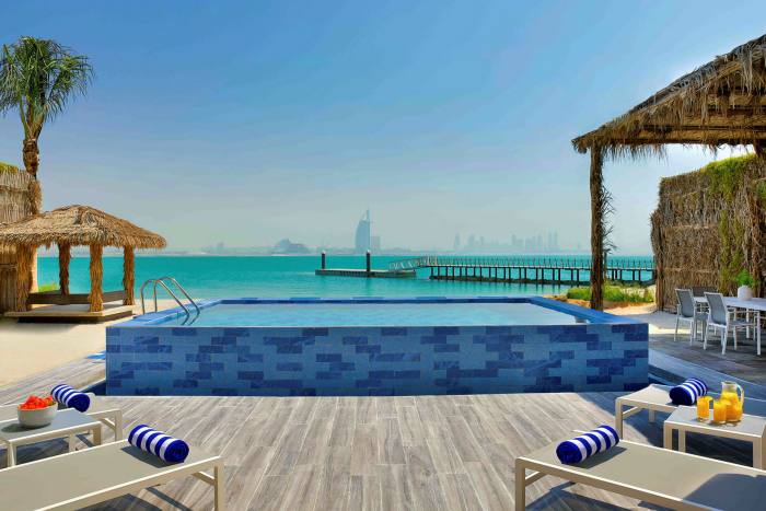 A villa with a private pool, with Dubai's distinctive Burj Al Arab hotel seen in the distance 