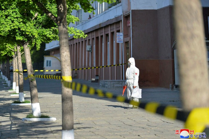 In this photo provided by the North Korean government, a worker in protective gear stands on an empty sidewalk in Pyongyang on Tuesday