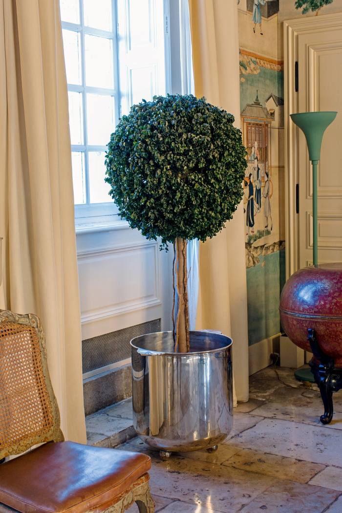 Artificial box trees in silvered brass cachepots line the dining room