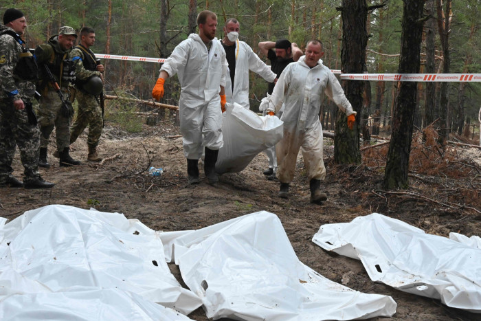 Forensic technicians carry a body bag in a forest on the outskirts of Izyum