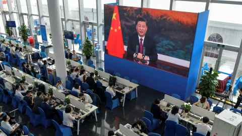 Journalists watch a screen showing China’s president Xi Jinping delivering a speech in April