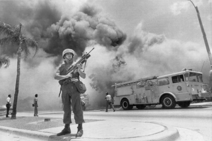 Smoke rises behind a a National Guardsman during race-related riots in Miami in 1980