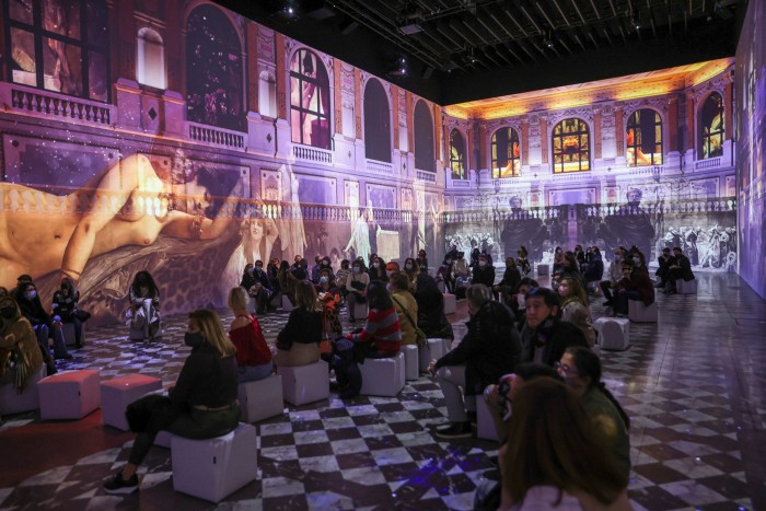 People sit and watch as artworks by Gustav Klimt are projected on to the walls of the Matadero as part of an immersive experience
