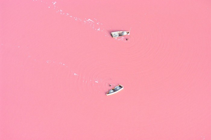 An aerial view of boats on a surface of pink