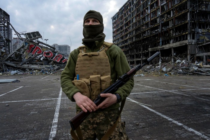 A soldier stands in front of wrecked buildings in Kyiv 