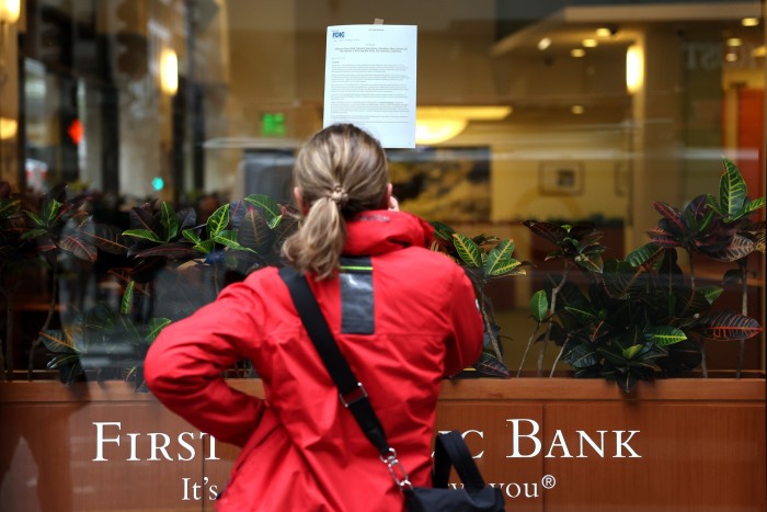 A passerby stops to read a posted announcement from the FDIC about the seizure of First Republic and sale to JPMorgan 