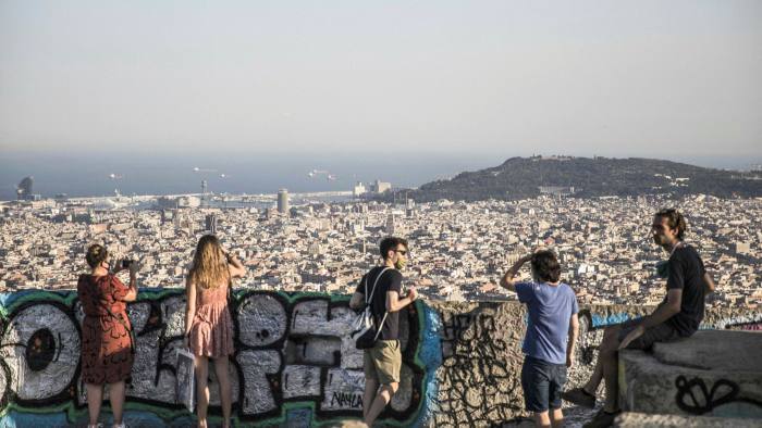 Visitors look over the city Barcelona from the Bunkers del Carmel viewpoint in Barcelona, Spain,