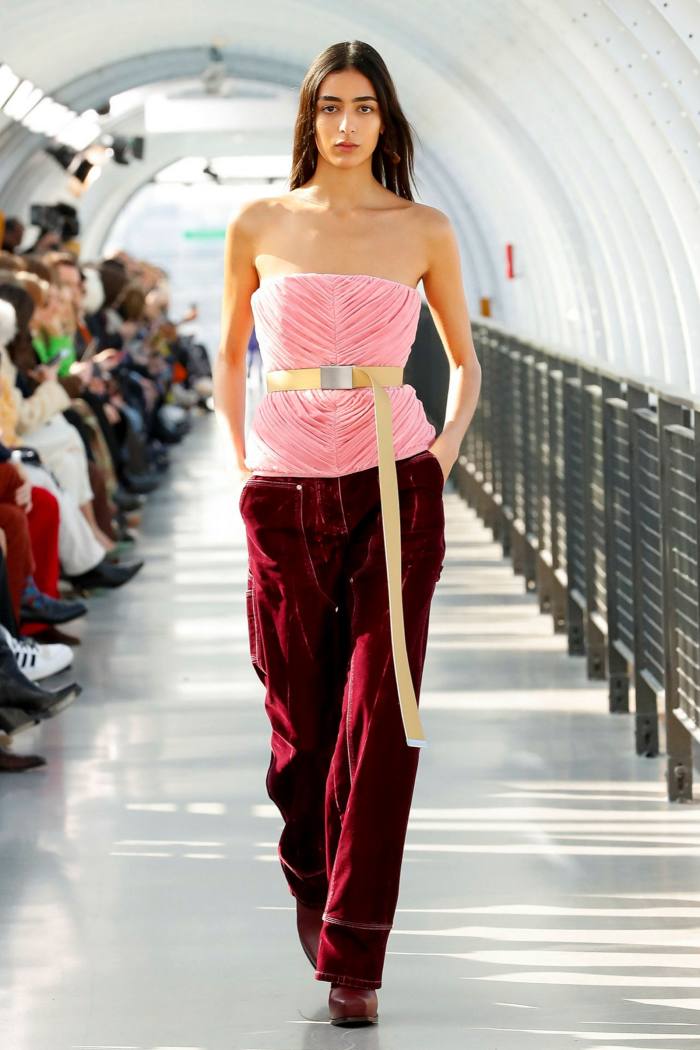 A model wears a Stella McCartney pink belted sleeveless top with dark red wide trousers