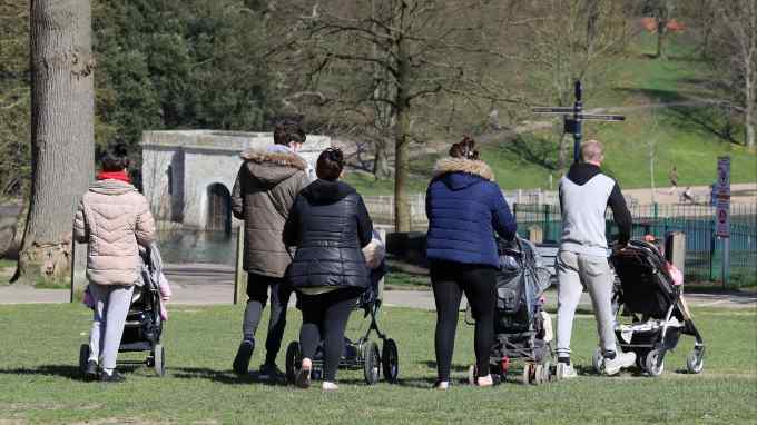 Parents push their young children through a park