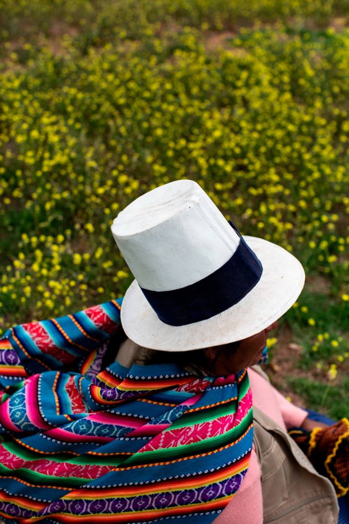A woman works in a field wearing a blanket and a white hat
