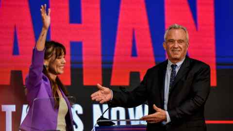 Nicole Shanahan waves to the crowd as Robert F Kennedy Jr gestures at her with both arms