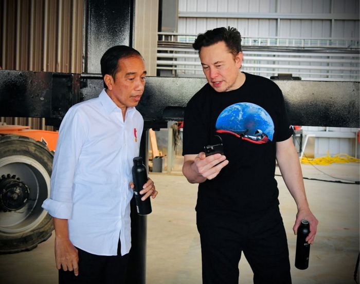 Joko Widodo talks with Elon Musk in a large aviation hanger