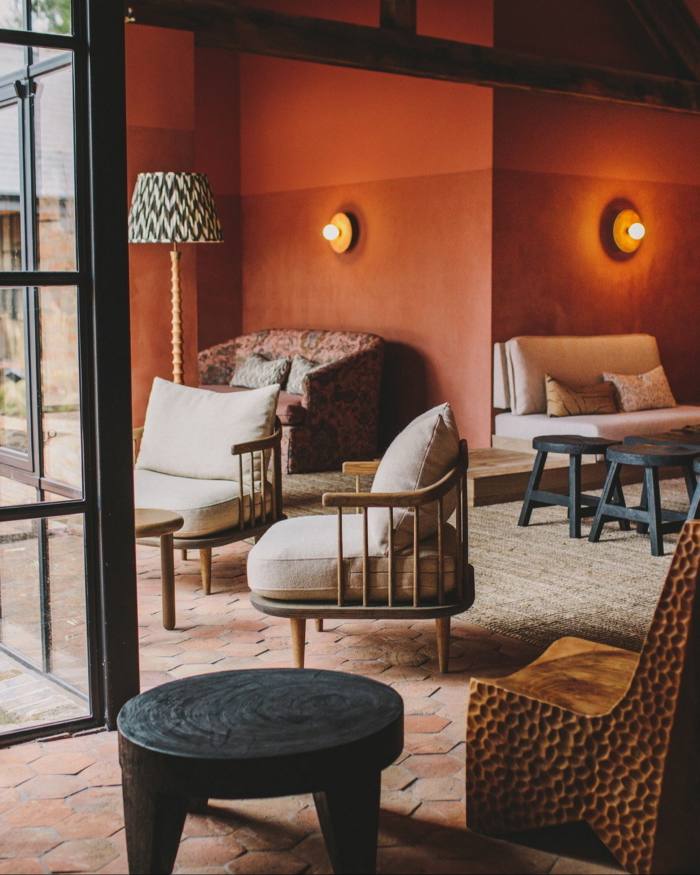 Sofa krim dan kerusi di dinding berwarna terracotta di ruang istirahat Grace & Savour
