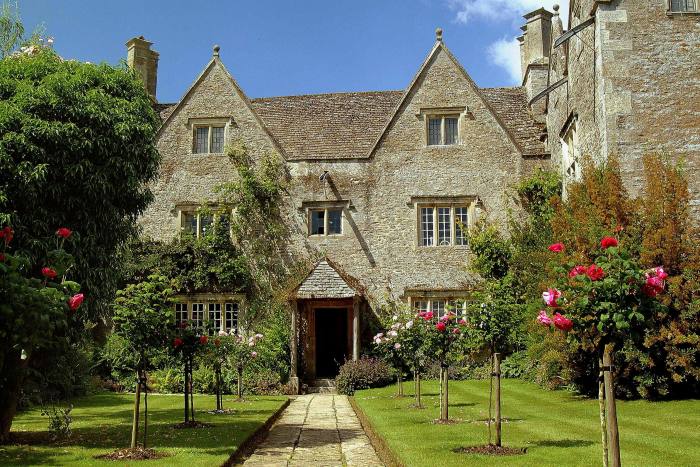 Exterior of Kelmscott Manor, with trees and cut grass at the front