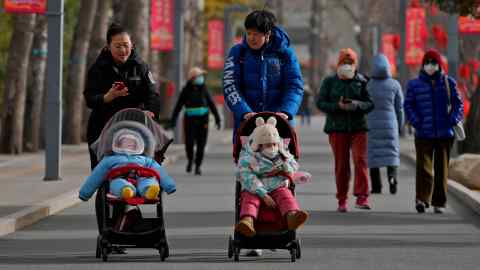Wanita berjalan bersama anak kecil mereka ketika penduduk melawat taman awam di Beijing