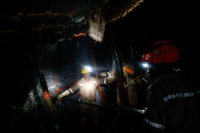 Mine workers operate a drill in a shaft in Westonaria, South Africa