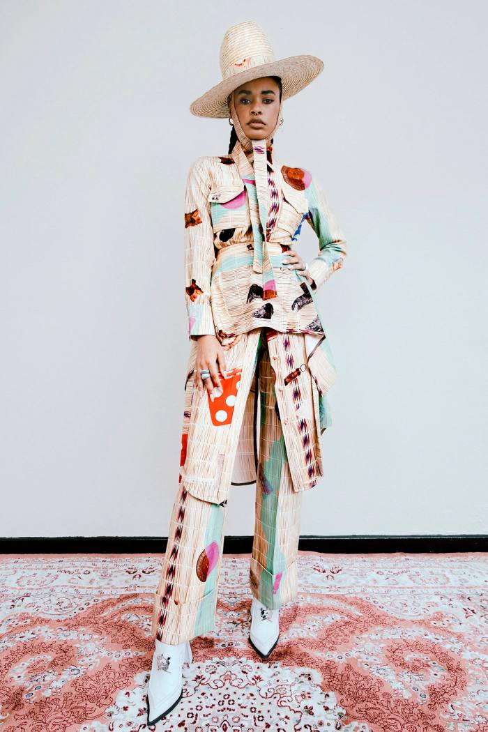 Model wears a long jacket and matching trousers with geometric and straw hut print