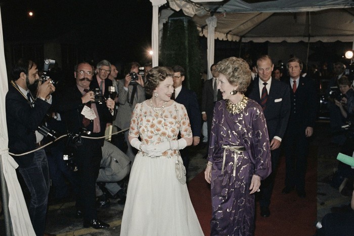 Queen Elizabeth II, left, chats with first lady Nancy Reagan as they enter Stage 9 at 20th Century Fox Studios to attend a gala dinner party honoring the queen and hosted by Mrs.  Reagan