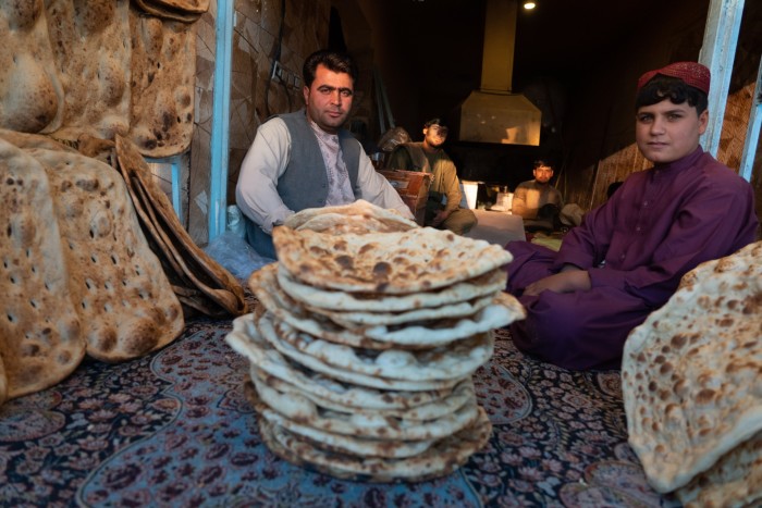 Two men sit behind a pile of flatbreads