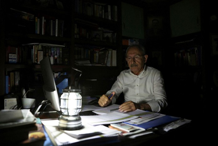 Kemal Kilicdaroglu works at desk with a hand lamp 