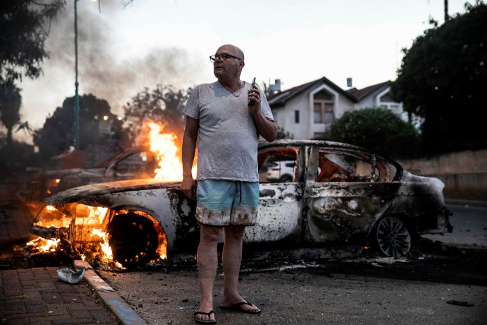 Jacob Simona stands by his burning car during clashes with Israeli Arabs and police in the Israeli mixed city of Lod