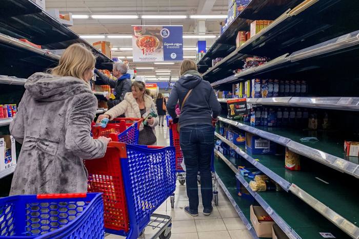 Customers maneuver shopping carts beside depleted food shelves inside a Carrefour SA supermarket in Brussels