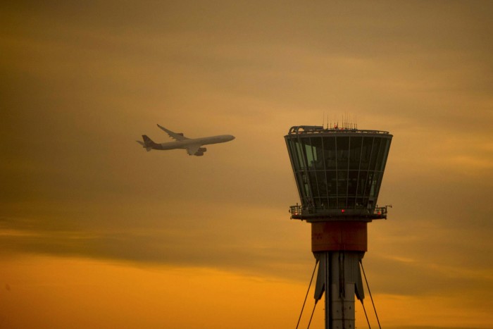 A passenger aircraft operated by Virgin Atlantic Airways flies past a control tower at London Heathrow Airport