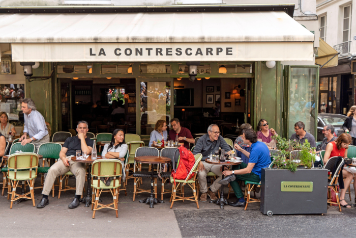 A cafe terrace where people sit and watch a Paris street