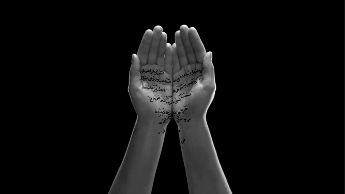 Two hands held aloft and close together with Arabic writing superimposed onto the palms