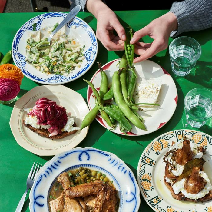 A woman’s hands shelling peas onto a plate at Towpath café. On the table are plates of dishes offered by the café