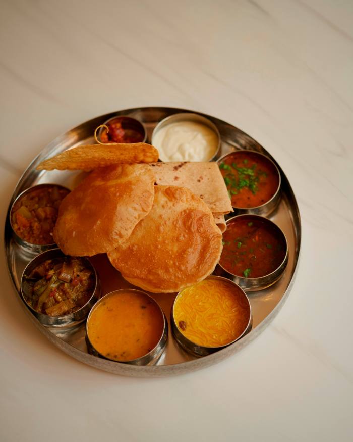 El thali del sur de la India en Woodlands: un plato metálico redondo lleno de platos pequeños y dosas.