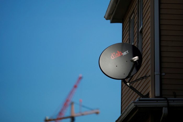 A Dish Network receiver hangs on a house in Somerville, Massachusetts