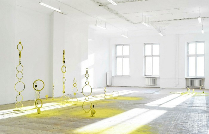 Small towers of yellow rings cast yellow shadows in a large white room